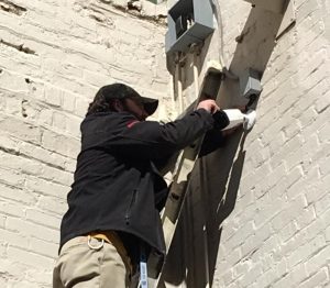 Image of Protection Systems, Inc. installing NC commercial video surveillance equipment to the outside of a building
